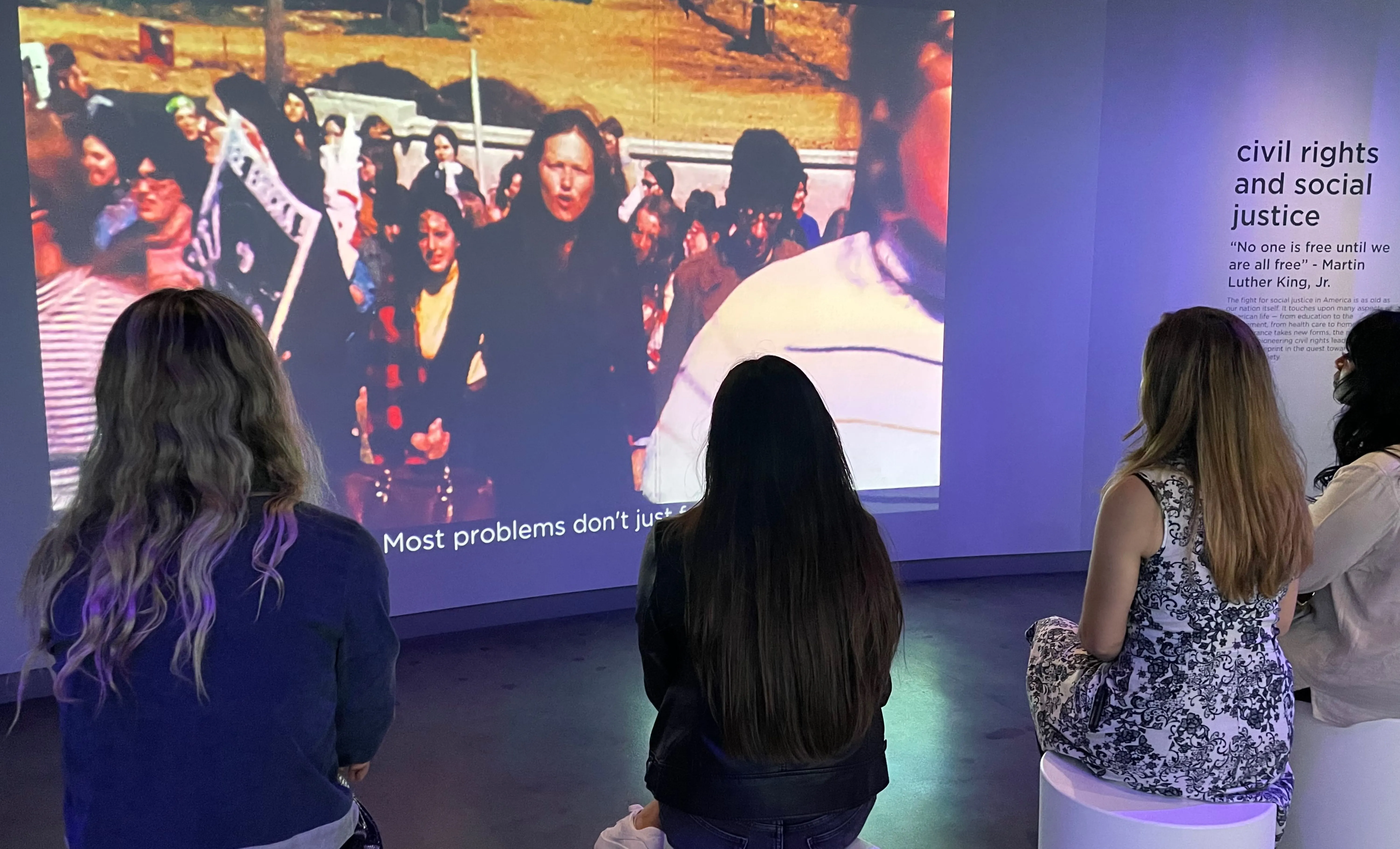 Visitors sit and watch a film on the history of civil rights and social justice movements throughout history.
